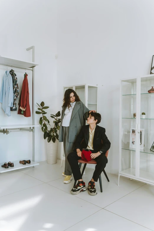 two women standing next to each other in a room, unsplash, bauhaus, sitting on a store shelf, wearing a fancy jacket, ulzzang, male and female