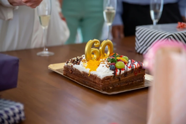 a birthday cake sitting on top of a wooden table, unsplash, he is about 6 0 years old, martin parr, gold, snacks