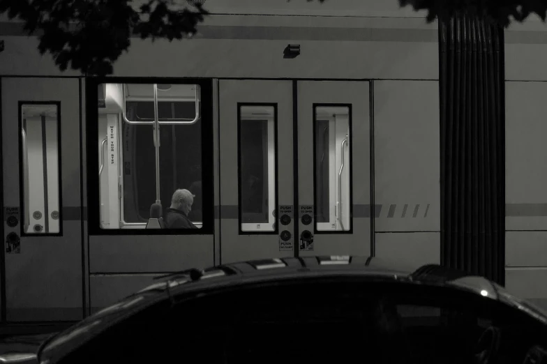 a black and white photo of a man looking out a train window, realism, at the taco bell drive through, moonlit parking lot, doors, taken in 2 0 2 0