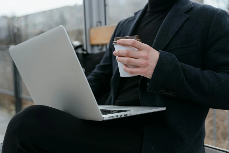 a man holding a cup of coffee and a laptop, by Carey Morris, pexels, a man wearing a black jacket, avatar image, grey, black