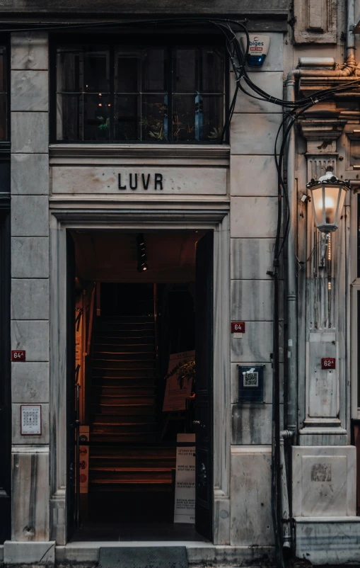 a building with a sign that says luvr on it, an album cover, by Ludovit Fulla, unsplash contest winner, gothic quarter, warm street lights store front, luxury fashion, stairway