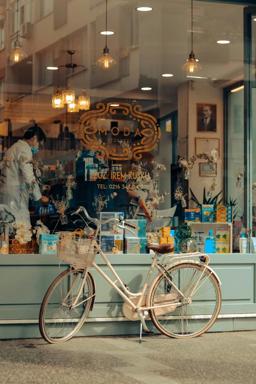 a bicycle is parked in front of a store, by Anna Findlay, pexels contest winner, art nouveau, cream and blue color scheme, people at work, apothecary, indoor shot