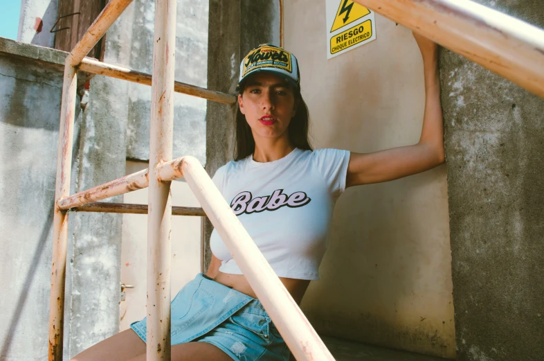 a woman sitting on the steps of a building, a cartoon, inspired by Elsa Bleda, trending on pexels, graffiti, trucker hat, with ripped crop t - shirt, babe, toiletpaper magazine