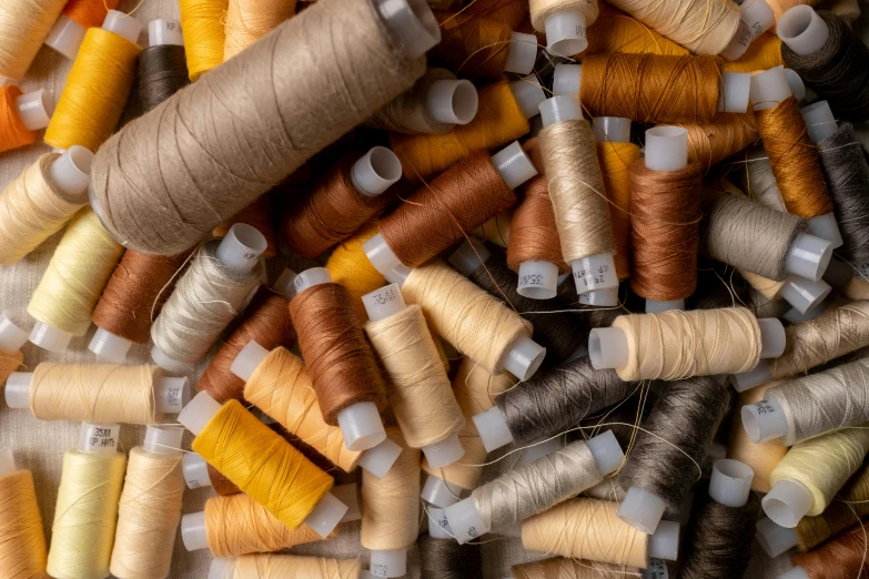 a pile of spools of thread sitting on top of a table, inspired by Christo, trending on pexels, renaissance, muted brown yellow and blacks, aerial view. hand stitching, thumbnail, 1 6 x 1 6