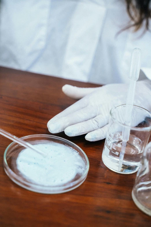 a close up of a person in a lab coat, strange ingredients on the table, slide show, water particulate, white gloves