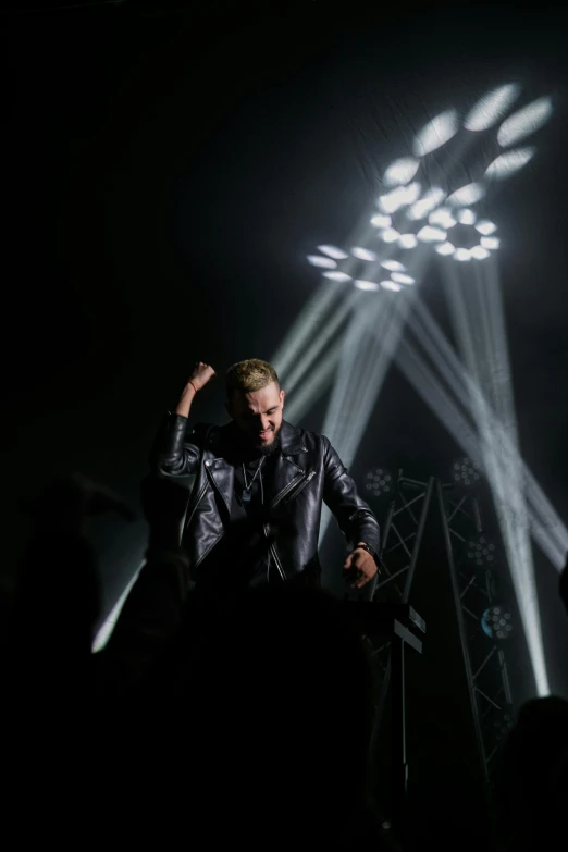 a man sitting on top of a stage in front of a crowd, an album cover, pexels, bauhaus, jamie campbell bower, concert lights, johan liebert, 15081959 21121991 01012000 4k