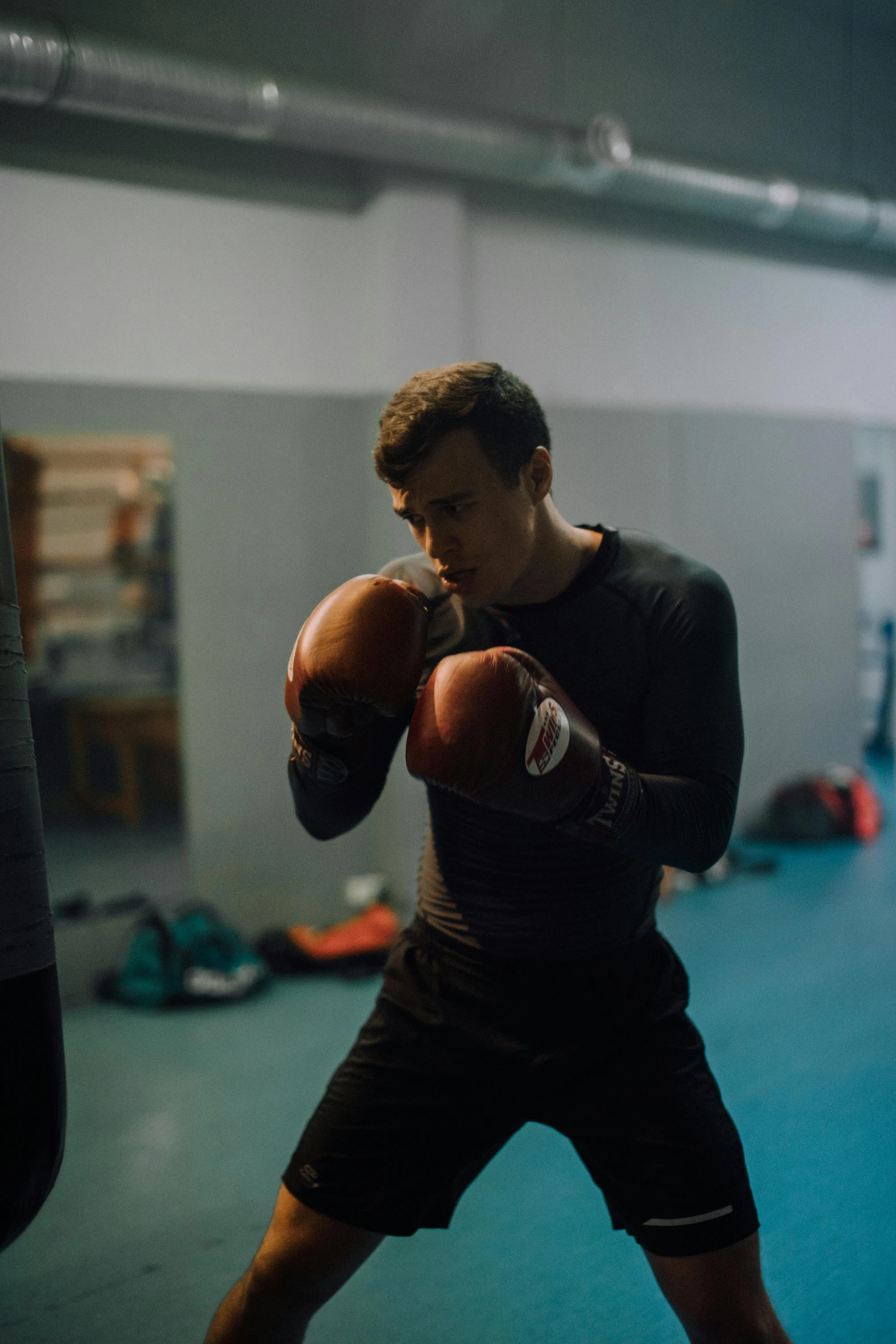 a man standing next to a punching bag, by Adam Marczyński, happening, sparring, square, cinematic, schools