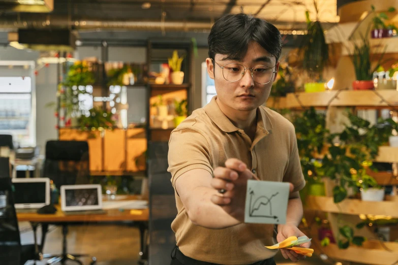 a man holding a piece of paper in his hand, by Jang Seung-eop, pexels contest winner, kinetic art, avatar image, small manufacture, nvidia and behance, wearing square glasses