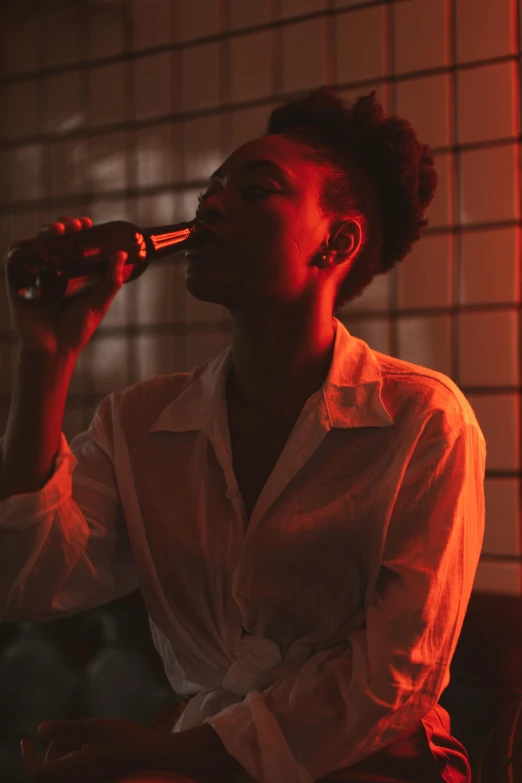 a woman sitting on a couch drinking from a bottle, inspired by Nan Goldin, pexels contest winner, renaissance, dark-skinned, man drinking beer, soft red lights, profile image