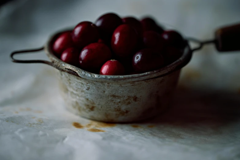 a bowl of cherries sitting on a table, a still life, by Emma Andijewska, pexels, process art, winter vibrancy, stew, grungy, silver