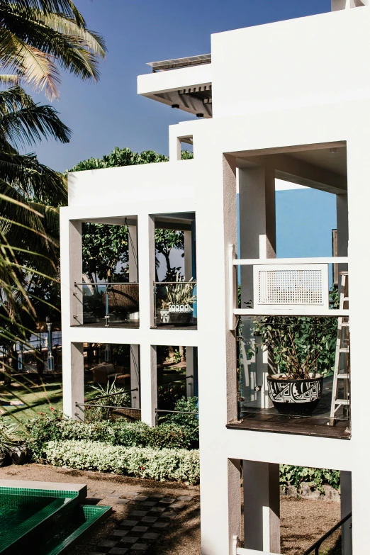 a white building sitting on top of a lush green field, inspired by Ricardo Bofill, visual art, golden hour in boracay, exterior view, beachfront, porches