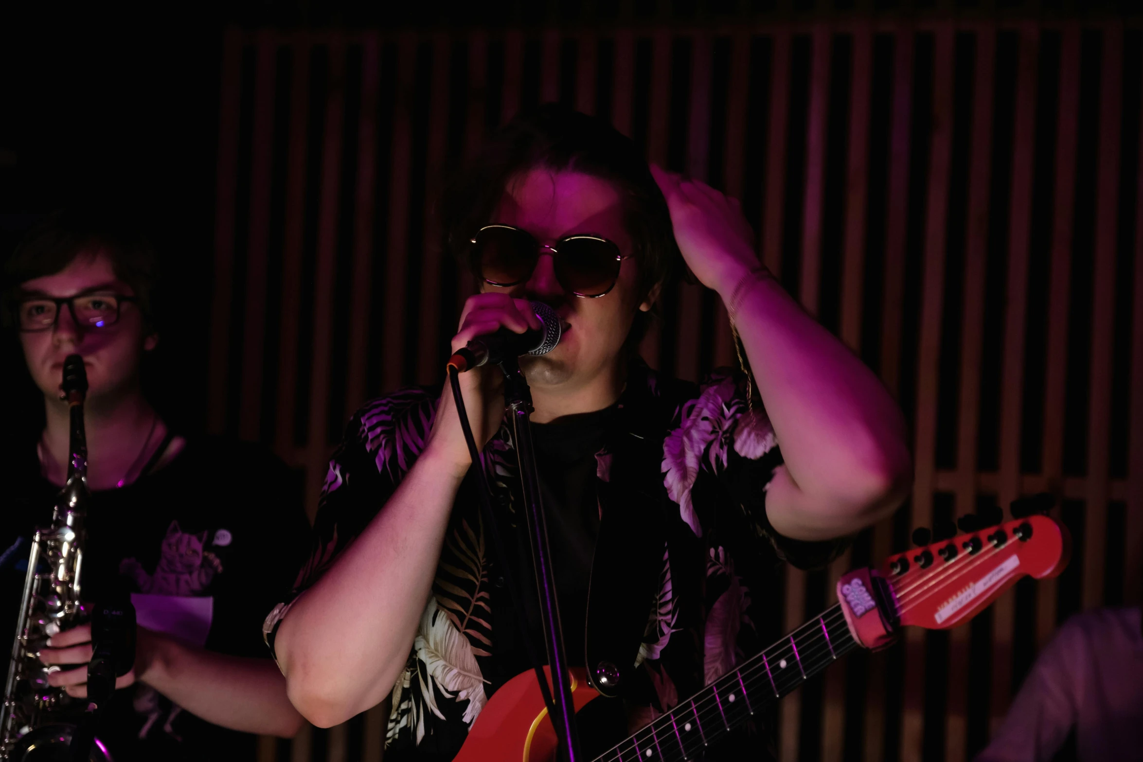 a woman singing into a microphone while holding a guitar, inspired by Lasar Segall, with sunglass, lachlan bailey, profile image, non-binary