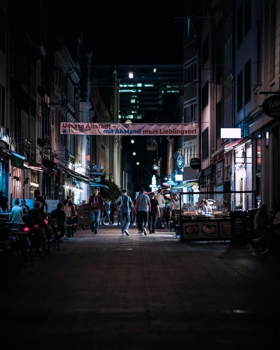 a group of people walking down a street at night, in a street, at night time, alleyway