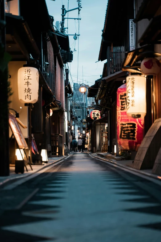 a narrow street lined with shops next to tall buildings, inspired by Watanabe Shōtei, trending on unsplash, evening lanterns, quaint village, buildings carved out of stone, fujifilm”