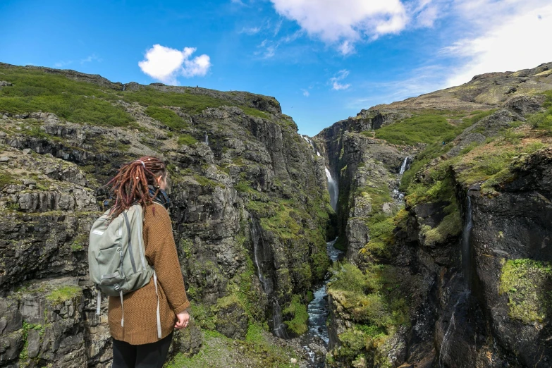 a woman standing in front of a waterfall, by Terese Nielsen, pexels contest winner, hurufiyya, gungnir, looking down at the valley, thumbnail, fully functional