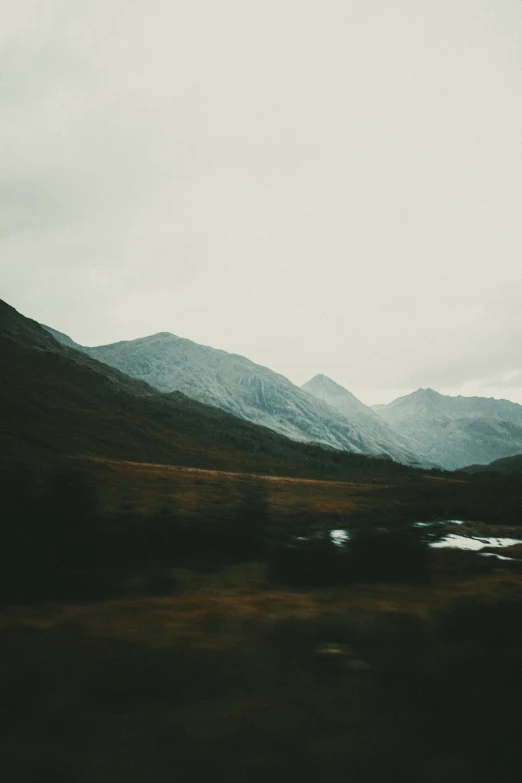 a view of the mountains from a moving train, a polaroid photo, inspired by Elsa Bleda, unsplash contest winner, scottish highlands, gray skies, autumnal, high quality photo