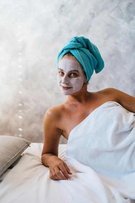 a woman laying in bed with a towel on her head, a portrait, trending on pexels, renaissance, face mask, candy treatments, smiling spartan, pale blue skin