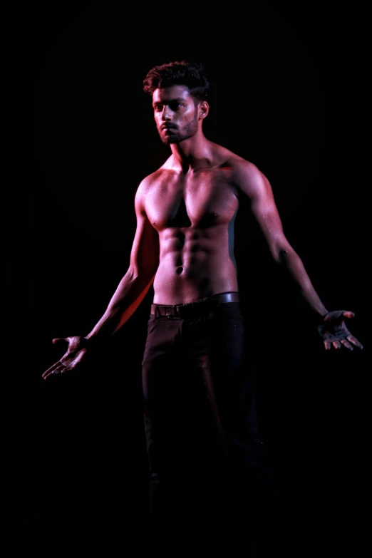 a shirtless man standing in front of a black background, by Byron Galvez, conceptual art, dramatic lighting and colors, actor, [ adamantly defined abs ]!!, dance