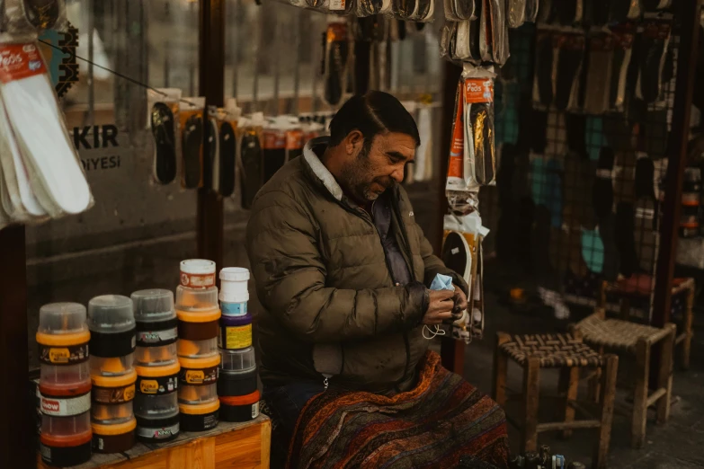 a man that is sitting down in front of a store, pexels contest winner, crafts, iranian, avatar image, sneaker photo