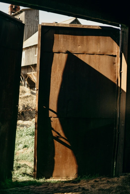 an open door to a barn with a barn in the background, inspired by Andrew Wyeth, unsplash, conceptual art, cast shadows, rusted panels, photo taken on fujifilm superia, reflected light