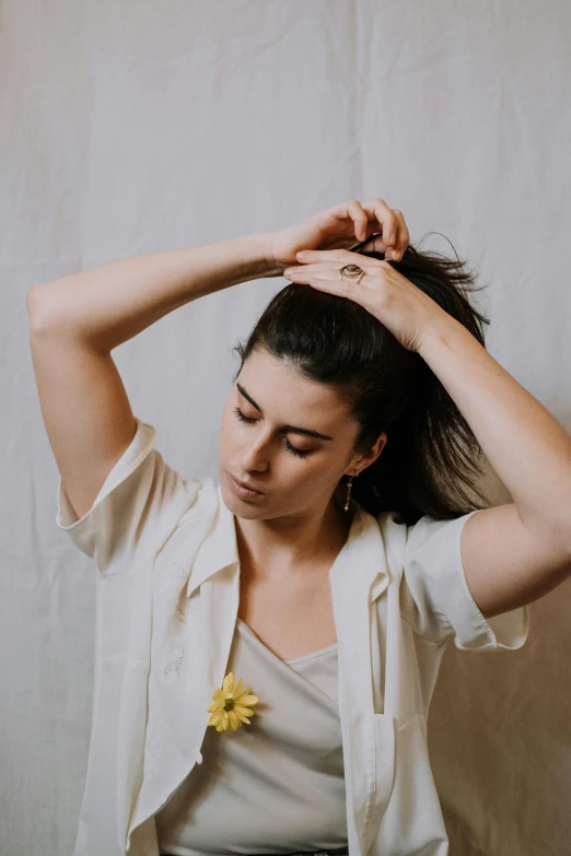 a woman with a yellow flower in her hair, an album cover, trending on pexels, wearing a white button up shirt, hands in her hair. side-view, charli bowater, indoor picture