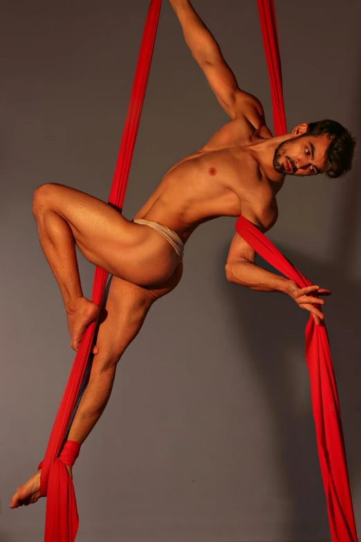 a man flying through the air while holding onto a red cloth, an album cover, inspired by Roberto Ferri, arabesque, athletic tall handsome guys, harnesses, slide show, lgbtq