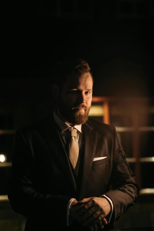 a man in a suit standing in a dark room, a portrait, inspired by Ramon Pichot, pexels contest winner, bearded, instagram post, lachlan bailey, gold suit