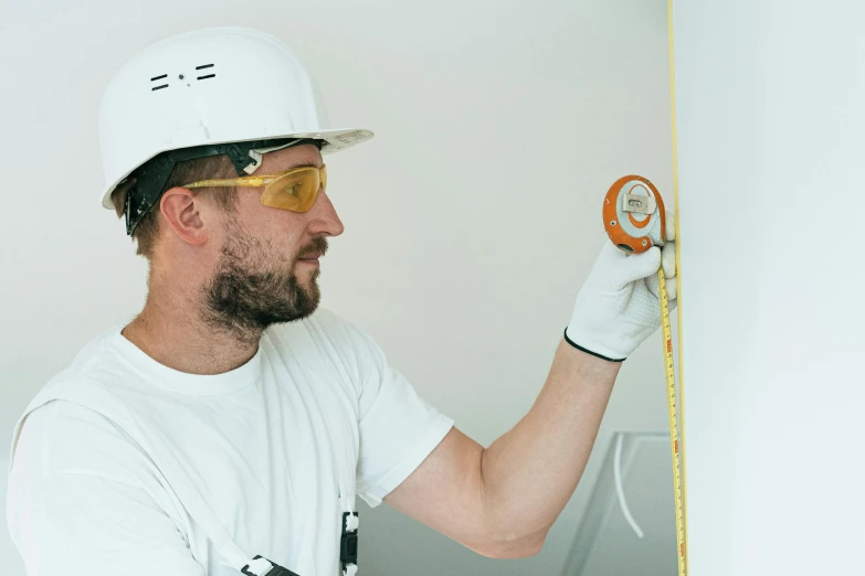 a man measuring a wall with a tape, by Évariste Vital Luminais, pexels contest winner, wearing plumber uniform, profile image, round format, professional profile photo