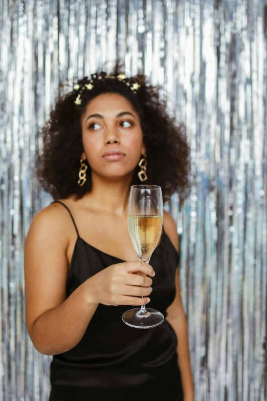 a woman in a black dress holding a glass of champagne, pexels contest winner, happening, curly afro, wearing silver dress, concerned, promotional image