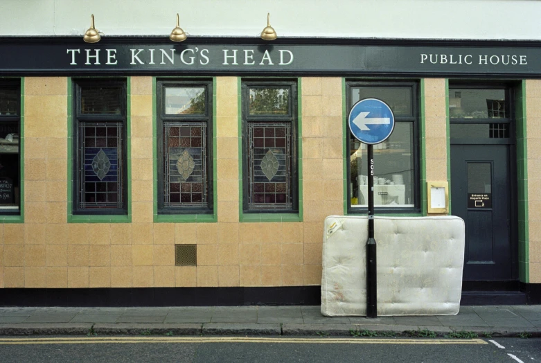 there is a mattress in front of the king's head public house, an album cover, by Ian Hamilton Finlay, trending on unsplash, hyperrealism, high forehead, big crown adorned with emerald, heads, long shot kodak portra 4 0 0