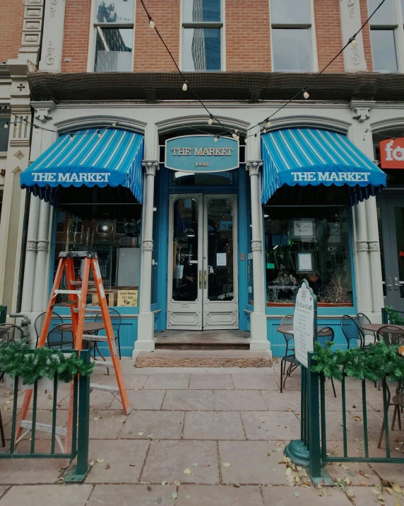 a building with a blue awning in front of it, market street, profile image, the madhatter, exterior photo