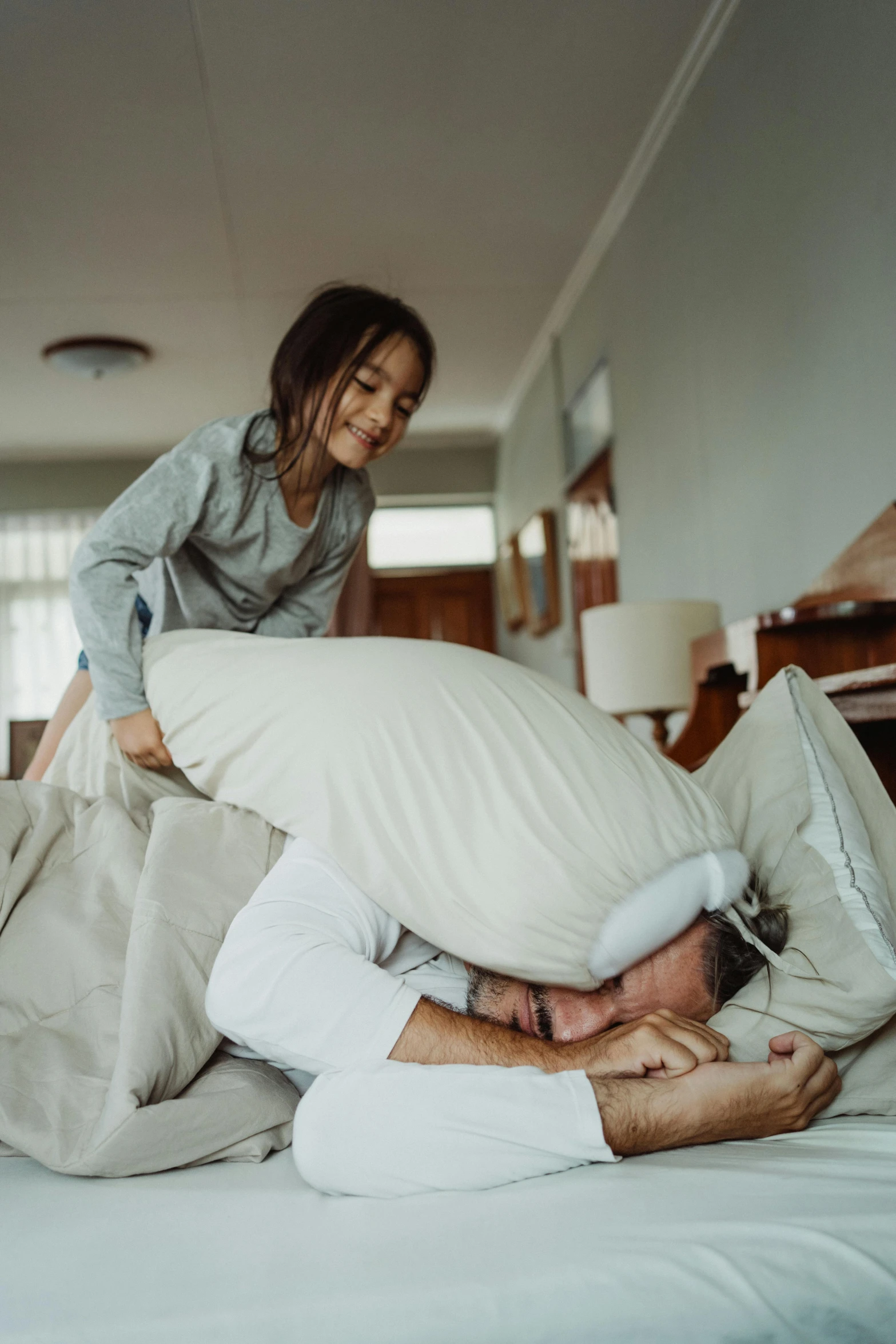 a man laying on top of a woman on a bed, pexels contest winner, happening, families playing, an ahoge stands up on her head, dad energy, pillows