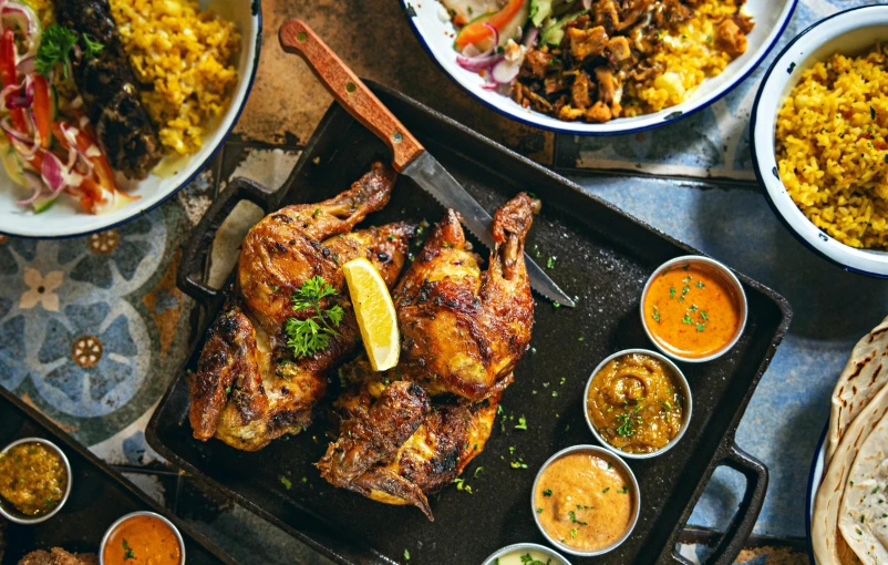 a table topped with lots of different types of food, pexels contest winner, hurufiyya, chicken, front facing shot, middle eastern skin, indian