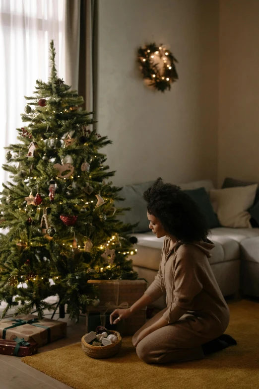 a little girl sitting on the floor in front of a christmas tree, photo of a black woman, profile image, apartment, pine