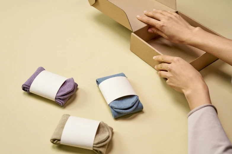 a person putting a pair of socks in a box, by Eden Box, minimalism, in muted colours, various posed, folded, scrolls