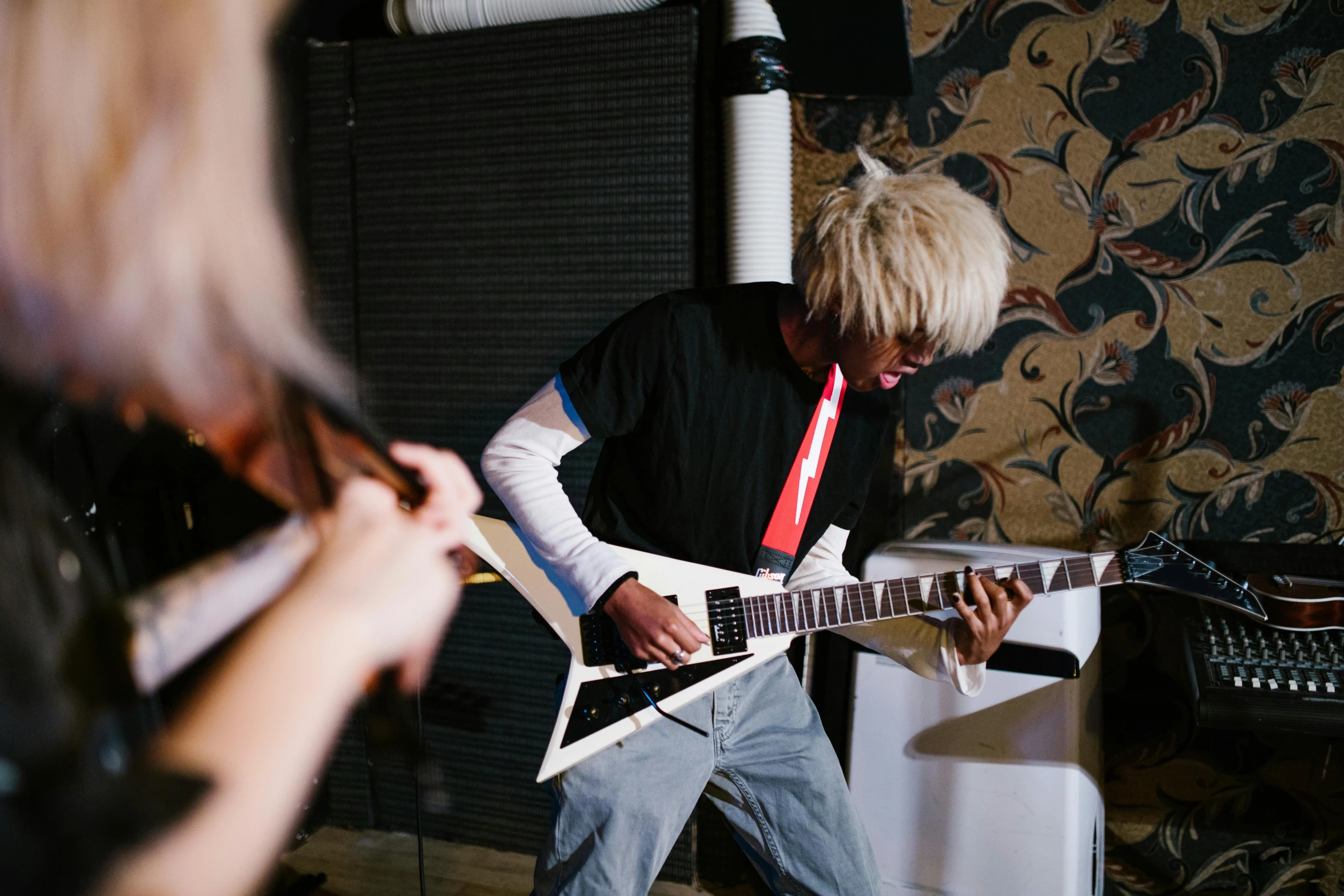 a man that is playing a guitar in a room, an album cover, inspired by Tadanori Yokoo, unsplash, master of puppets, a blond, live performance, crystal castles