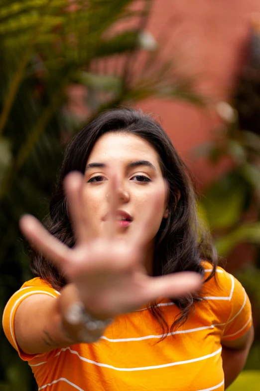 a woman making a stop sign with her hands, by Alejandro Obregón, pexels contest winner, nose, headshot profile picture, pointing at the camera, fernanda suarez