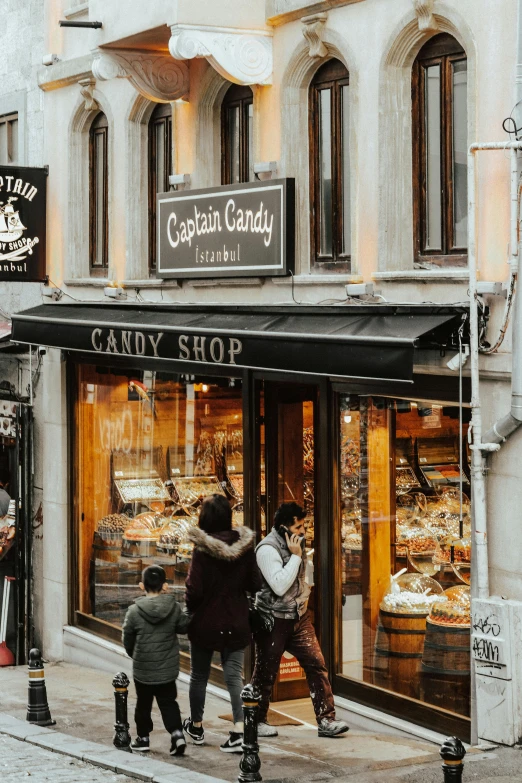 a group of people walking down a street next to a building, candies, the store, captain, canva