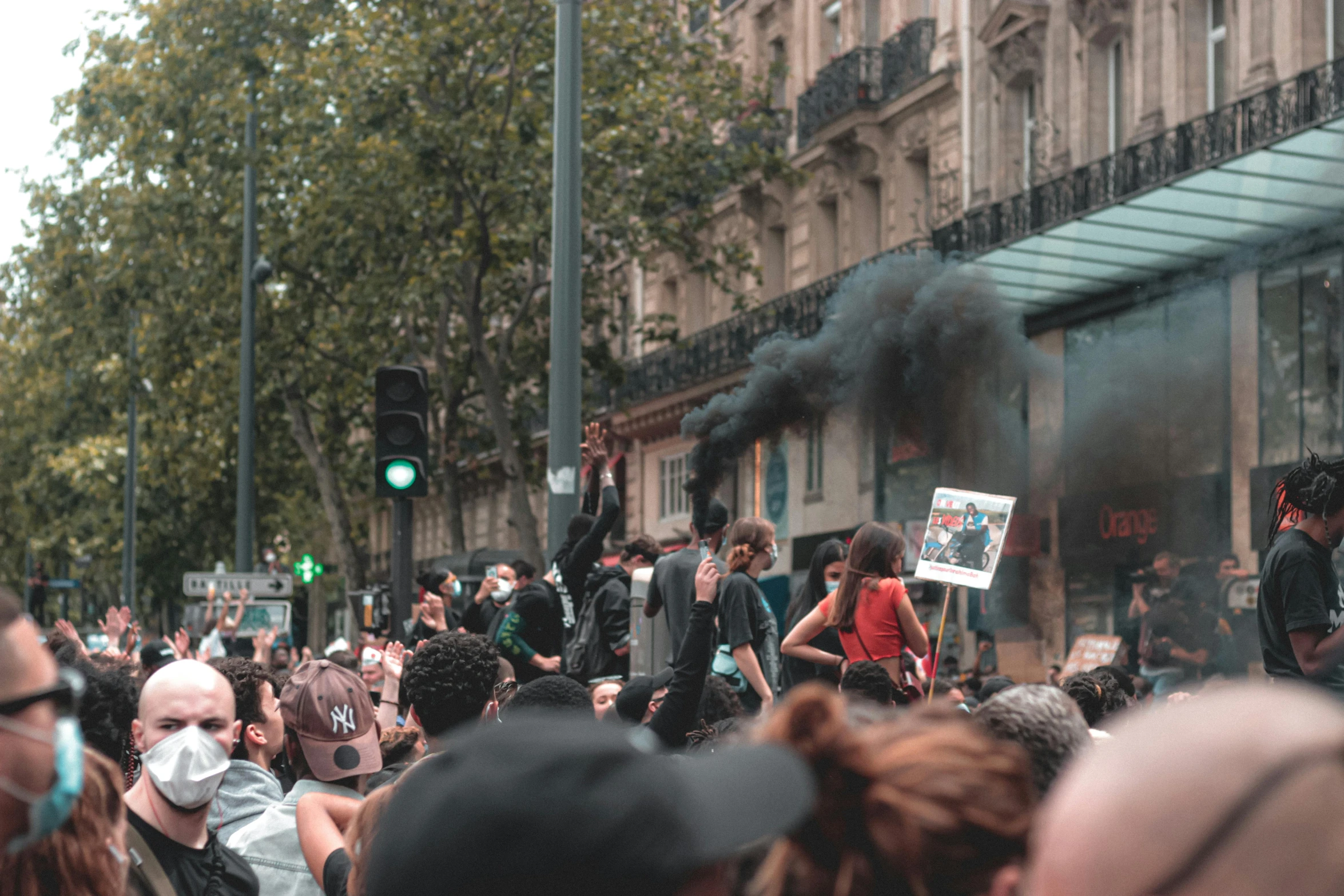 a group of people standing on top of a street, chaotic riots in 2022, traveling in france, buildings and smoke, placards