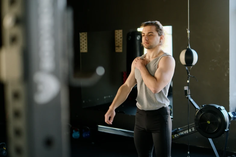 a man standing next to a machine in a gym, by Meredith Dillman, pexels contest winner, looking from shoulder, stretch, lachlan bailey, xqc