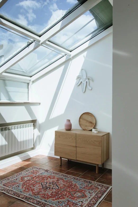 a room with a skylight and a rug on the floor, inspired by Constantin Hansen, unsplash contest winner, light and space, vignette of windowsill, interior white wall, solar, sustainable materials