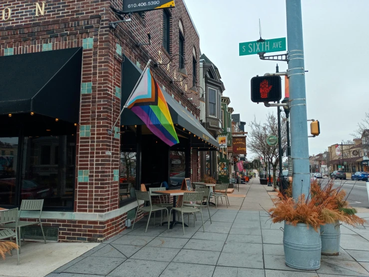 a restaurant on the corner of a city street, a photo, pride flag in background, chesterfield, cozy setting, square