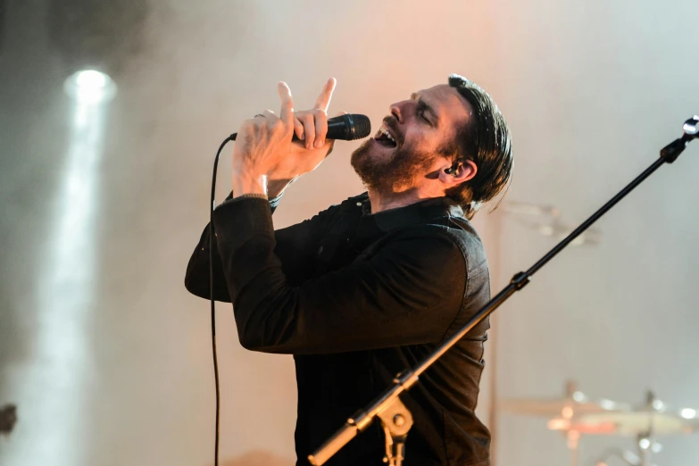 a man singing into a microphone on stage, by Niko Henrichon, pexels contest winner, bauhaus, matt berry, the tesseract, profile image, square