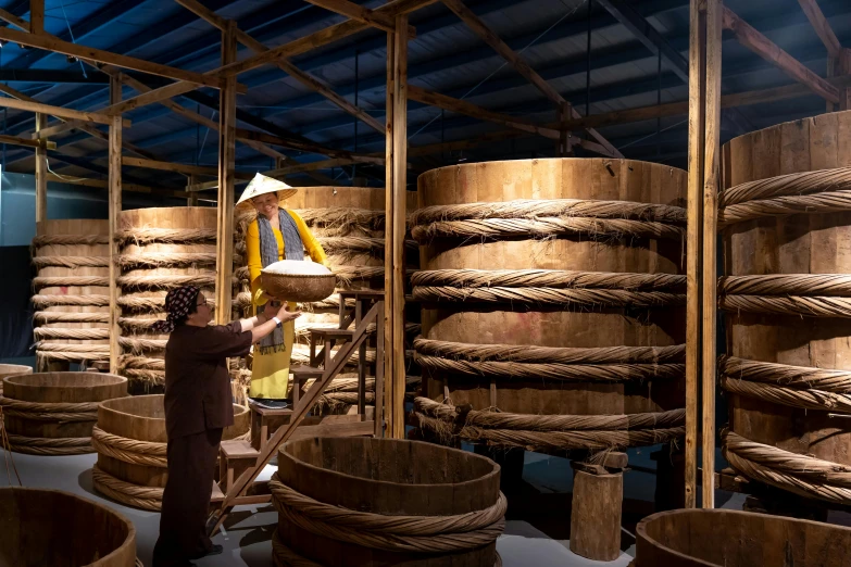 a woman standing in a room filled with wooden barrels, inspired by Li Di, warping, zezhou chen, silo, incense