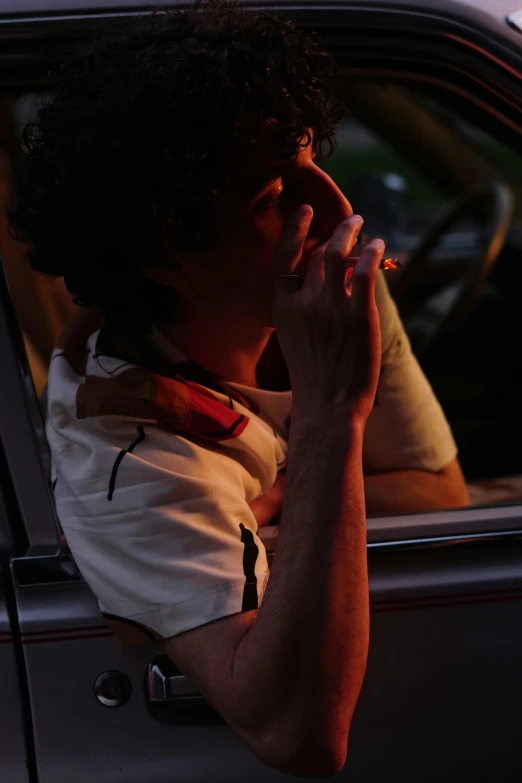 a man sitting in a car talking on a cell phone, an album cover, inspired by Nan Goldin, unsplash, renaissance, praying with tobacco, finn wolfhard, summer evening, side profile shot