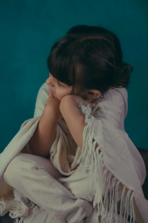 a little girl sitting on the floor wrapped in a blanket, an album cover, by Elsa Bleda, pexels, hurufiyya, crossed arms, pouty, ignant, alanis guillen