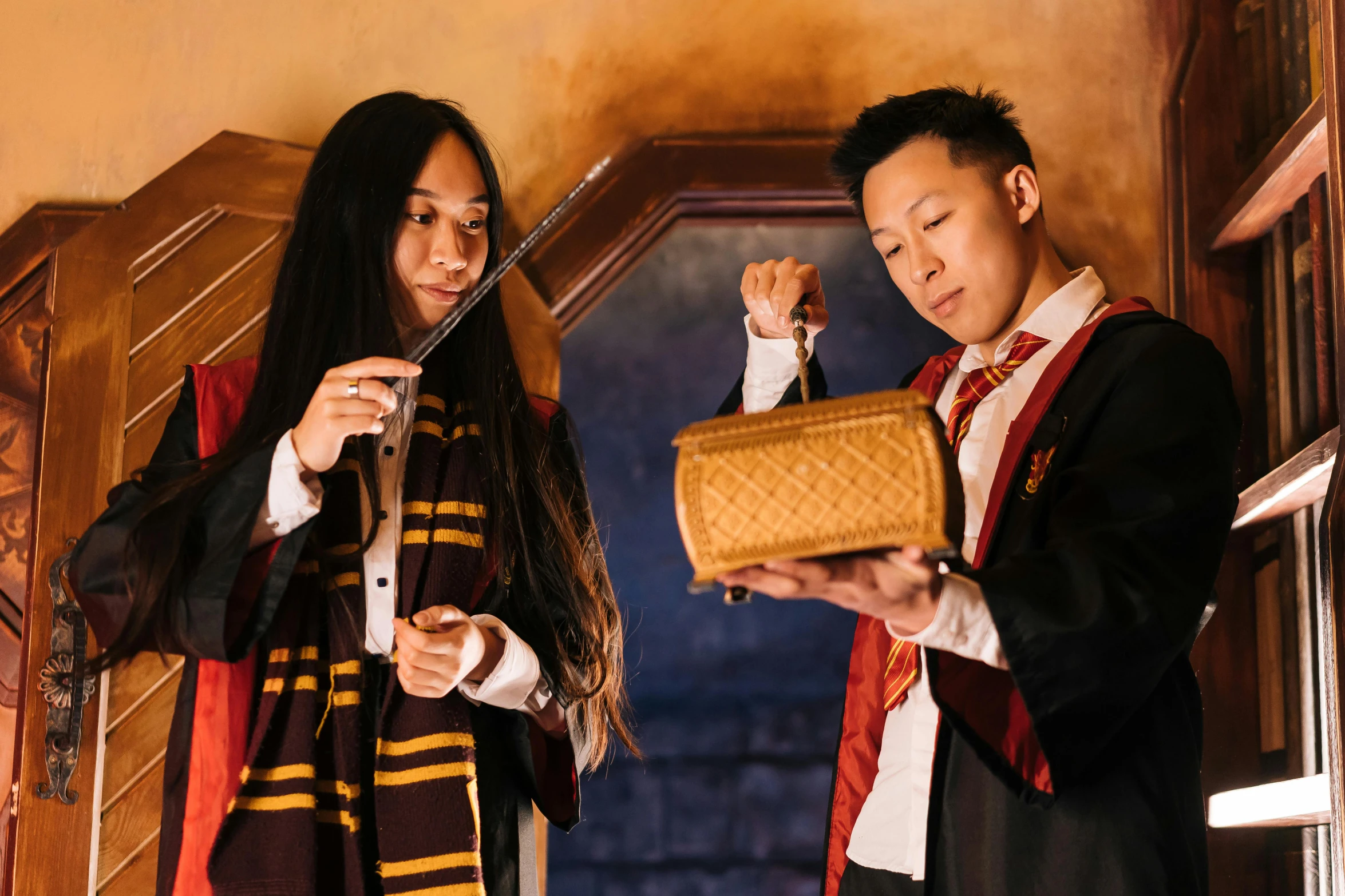 a couple of people standing next to each other, by Fuller Potter, holding wands, darren quach, holding a baguette, set photo in costume