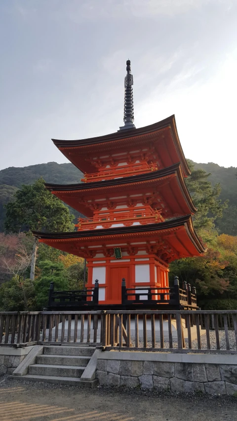 a red pagoda sitting on top of a lush green hillside, sōsaku hanga, dark grey and orange colours, square, high-quality photo, multiple stories