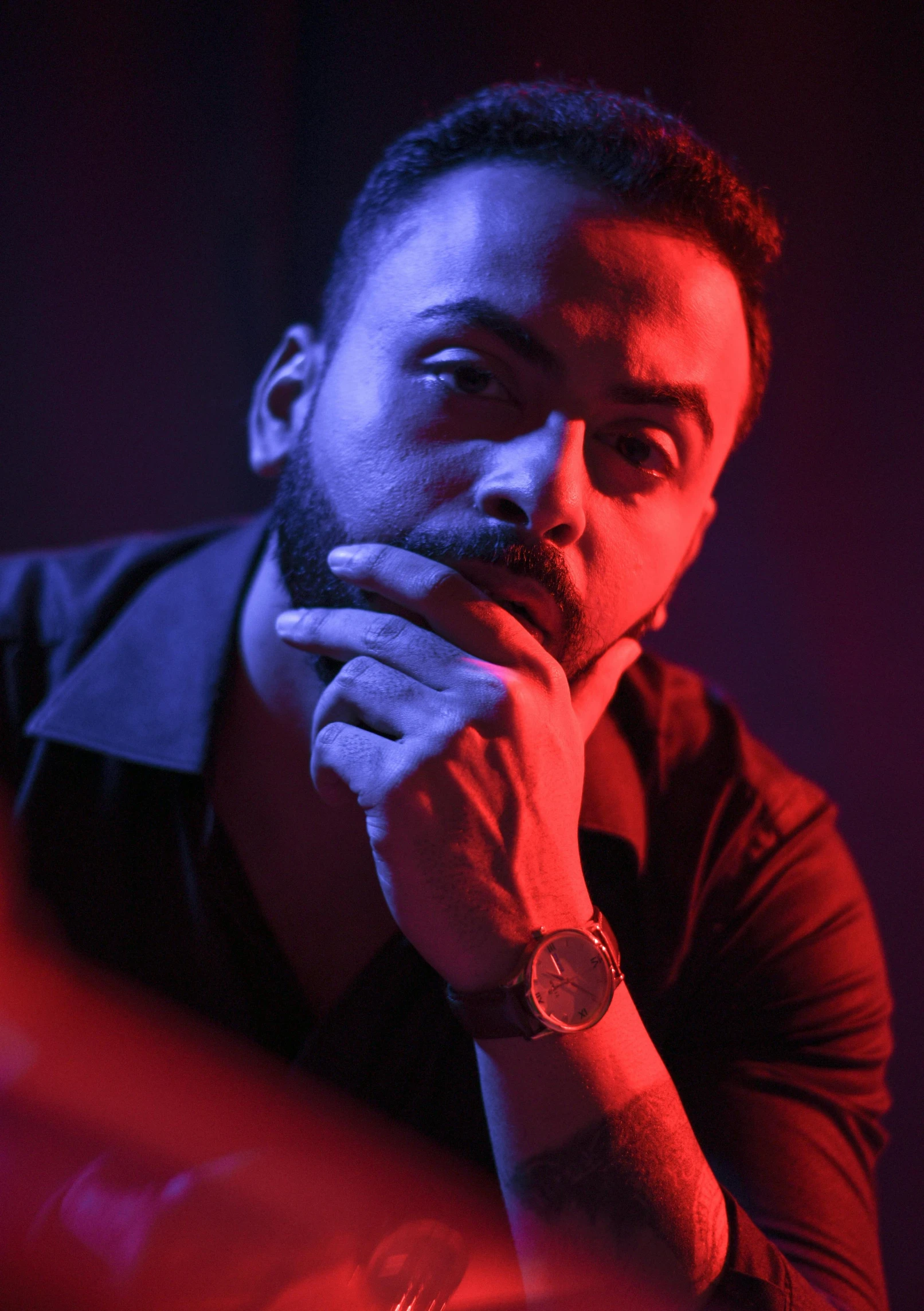 a man sitting at a table with his hand on his chin, an album cover, inspired by Nabil Kanso, pexels contest winner, les nabis, bisexual lighting, ( ( theatrical ) ), artem, vinayak