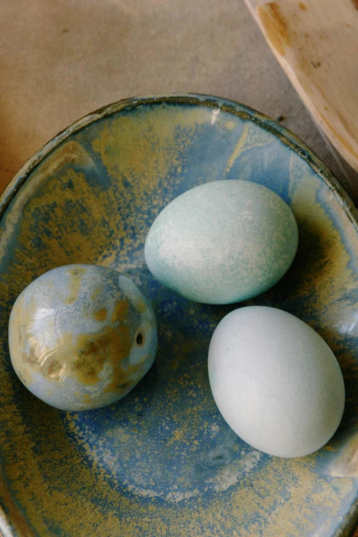 three eggs in a bowl on a table, process art, with celadon glaze, cerulean, various sizes, slate